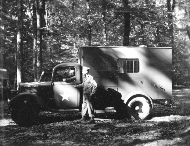 Captain Newman, Commanding Officer of the 1230 MP Company, stands next to the MP's version of the Black Maria in the Foret de Marchenoir near Orleans.