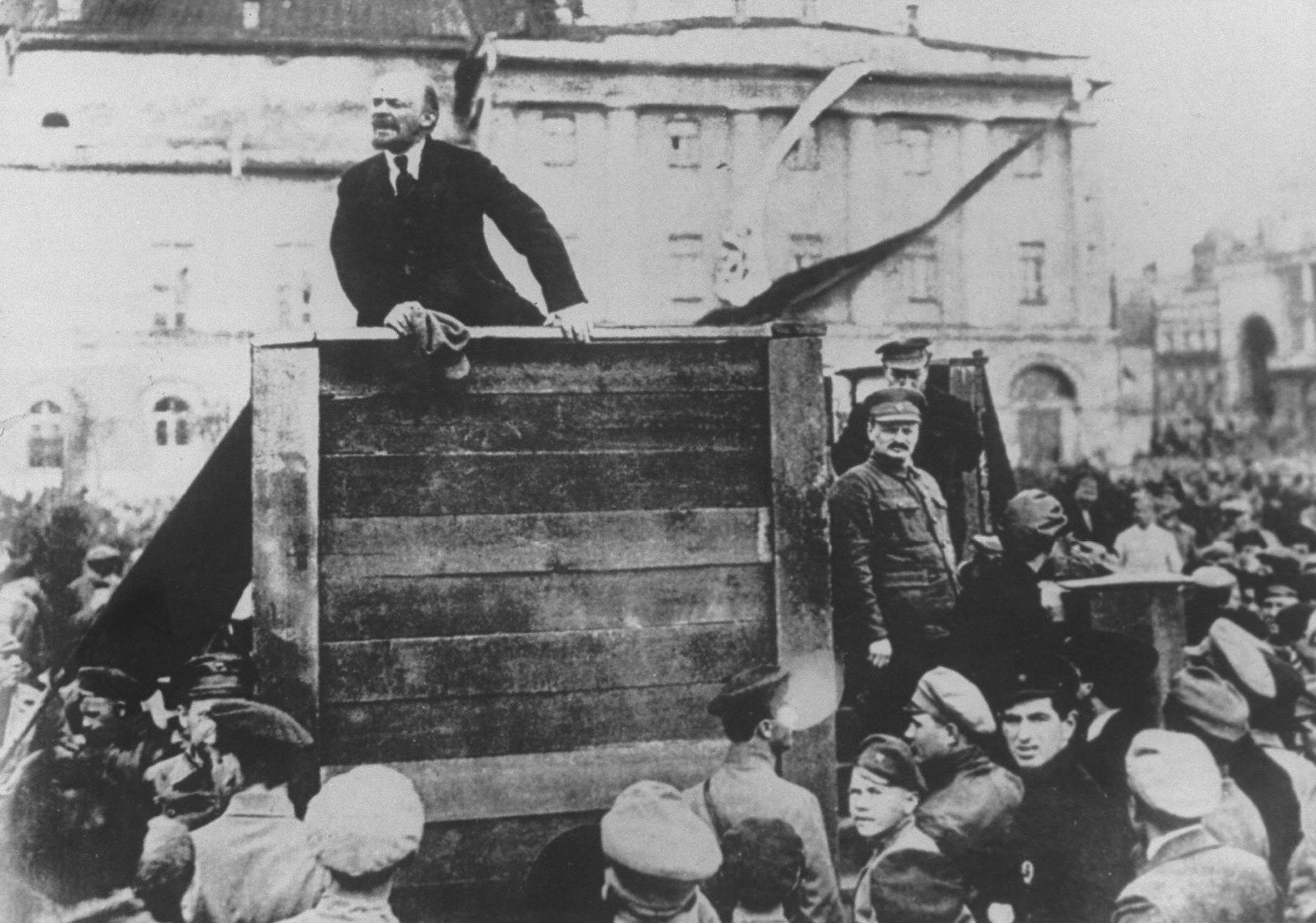 Vladimir I. Lenin haranguing a crowd, as Leon Trotsky stands on platform at right (photo was originally suppressed w. another figure substituted for Trotsky).